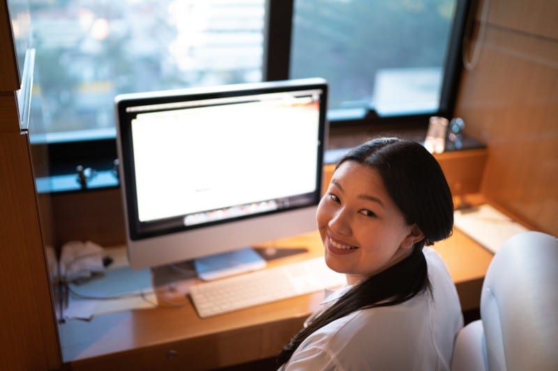 asian medical student smiling while attending pre med classes on desktop computer