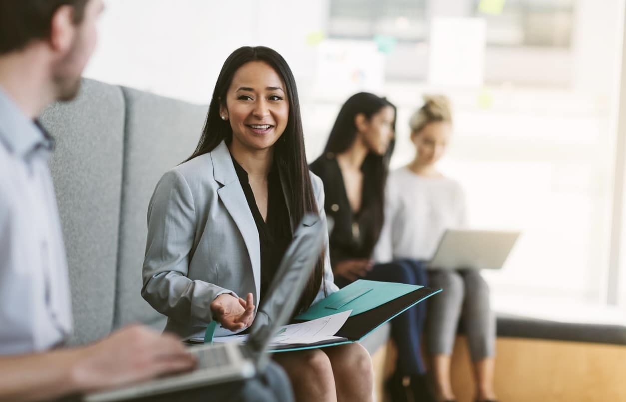 Multiracial young woman sits to discuss with work colleagues plans and ideas in modern coworking shared business office