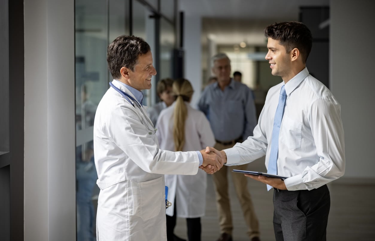 Medical sales representative greeting a doctor with a handshake at the hospital